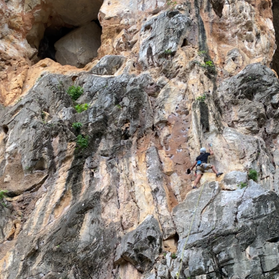 Climber beside giant round rock inside cave at Gua Damai