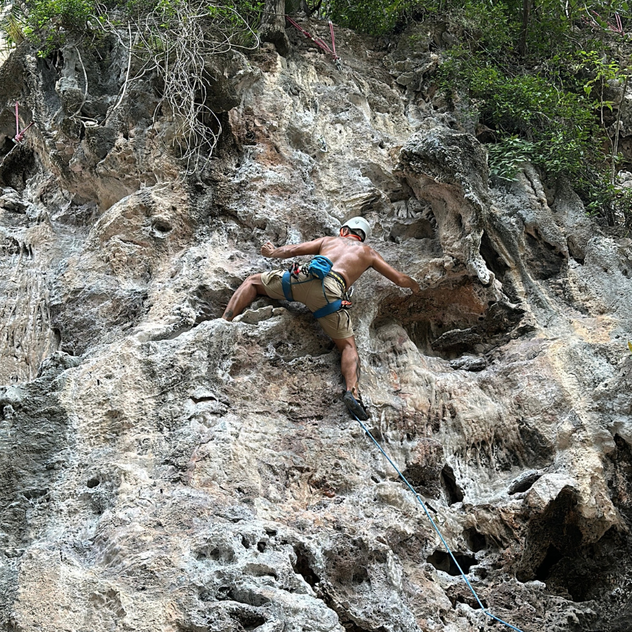 Climber navigating the crux of Ling Noi at Railay Beach, a technical move requiring precision and commitment.