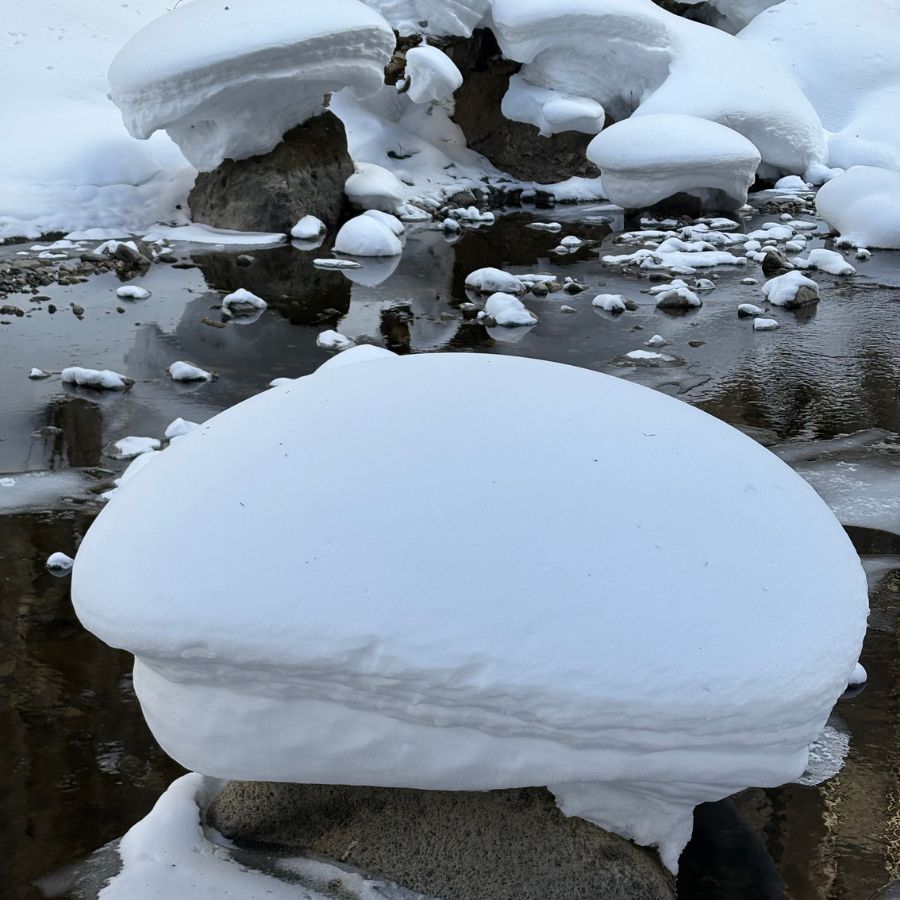 fluffy snow sitting on a rock in frozen river Hokkaido